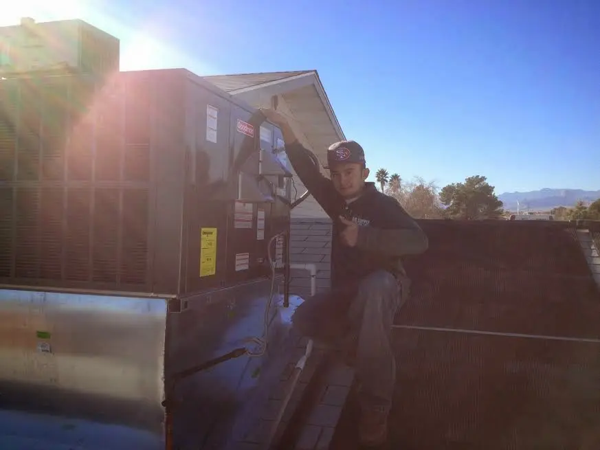 HVAC technician performing AC Tune-Up on a rooftop unit in Aztec